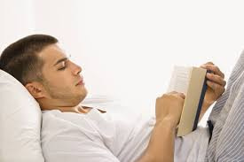 man reading a book in bed